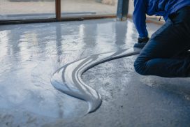 Worker expertly applying resin to a concrete floor for a smooth finish